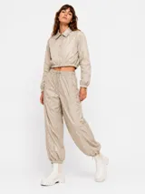 Pantalon estilo parachute verde militar con cintura elastizada ajustable mediante cordón, bolsillos laterales y puños ajustables en los tobillos.