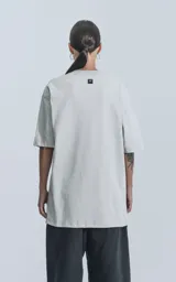 Remera de algodón premium color gris claro, corte oversize con hombros caídos y cuello redondo.