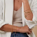 Esclava de alambre redondo en oro 9k con medalla colgante circular que presenta un diseño de estrella grabada con una circonia central.