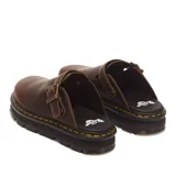 Muecas o zapatos destalonados Dr. Martens modelo Zebzag de cuero marrón, con tira ajustable con hebilla metálica y suela chunky acanalada con costura amarilla característica de la marca.