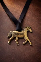 Collar con dije de caballo en tono dorado, montado sobre una tira de cuero negro.