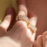 Anillo dorado con cristales ovalados engarzados y diseño infinito.