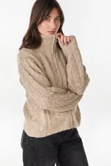 Campera de punto tejido color beige con diseño de ochos, cuello alto y cierre frontal completo.