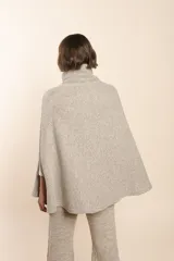 Capa color beige con textura de espiga, cuello alto con botones y aberturas laterales para los brazos. Confeccionada en lana fina sin teñir.