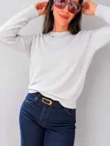 Suéter de tejido fino en color gris melange, con cuello redondo a la base y mangas largas. Presenta un diseño básico y versátil con puños y ruedo acanalados.