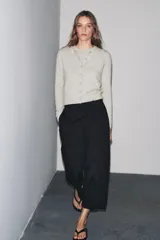 Chaqueta de lana 100% color gris claro, con cuello redondo, manga larga y cierre frontal con botones.