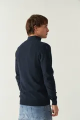 Sweater azul marino de punto con cuello alto y medio cierre con cremallera. Tiene mangas largas y logo bordado en el pecho. Corte regular.