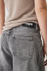 Jeans de corte barrel en tono gris deslavado, con diseño amplio y tachas decorativas a lo largo de las costuras laterales y los bolsillos delanteros.