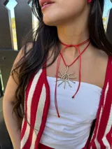 Collar con cordón ajustable color beige y dije de sol plateado.