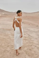 Vestido midi blanco con bordados florales perforados, escote en V, sin mangas y tirantes cruzados en la espalda.