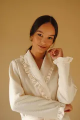 Bata larga color blanco, confeccionada en algodón capitoneado con diseño de espiga. Presenta volados en el cuello y puños, y lazo de ajuste en la cintura.