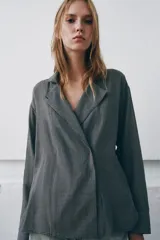 Camisa de corte oversize confeccionada en algodón, con estampado de cuadros pequeños en tonos grises. Presenta cuello solapa, cierre frontal con botones ocultos y mangas largas con puños rectos.
