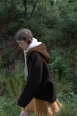 Chaqueta de punto color marrón con capucha desmontable en tejido técnico a tono. Presenta cierre frontal con cremallera, bolsillos delanteros y mangas largas con doble puño elástico.