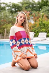 Sweater de punto con diseño geométrico multicolor y cuello redondo. El borde del cuello, puños y ruedo es de color salmón fluorescente.