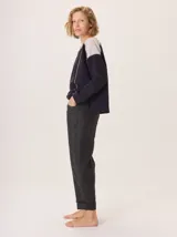 Pantalon de corte recto y tiro medio, confeccionado en tejido de lana con sutiles rayas verticales. Presenta bolsillos traseros aplicados, costuras reforzadas en las rodillas y ruedo con dobladillo.
