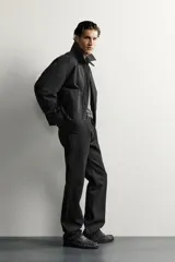 Jeans slim straight fit para hombre, confeccionados en denim de algodón negro sin lavados. Presentan diseño de tiro bajo, pierna recta y cinco bolsillos, con cierre frontal de botonadura.