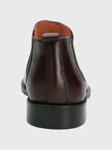 Bota tipo Chelsea de cuero en color bordó, con paneles laterales elásticos y suela de goma negra.