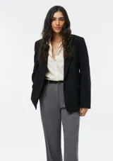 Camisa de corte clásico con cuello camisero, manga larga con puños vueltos y cierre frontal de botones. Presenta un diseño de rayas verticales finas en tono beige.