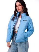 Chaqueta acolchada de corte regular, color celeste, con cierre frontal, cuello alto y bolsillos laterales. Presenta un parche con el logo de la marca en el pecho y puños con elástico.