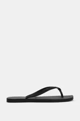 Sandalias planas de dedo tipo ojota, color negro, con diseño minimalista y suela de goma con textura en relieve.