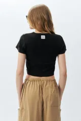 Top corto negro ajustado al cuerpo, de manga corta y cuello redondo.