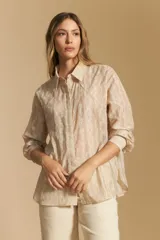 Camisa blanca de manga larga con textura calada o bordada, cuello camisero y corte holgado.