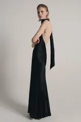 Vestido largo de satén negro con cuello halter subido y espalda descubierta. Presenta un diseño fluido con bajo en línea evasé.