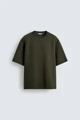 Sudadera de corte oversize confeccionada en tejido técnico de algodón con elasticidad, cuello redondo y manga corta. Presenta una tacha metálica decorativa en la parte posterior.