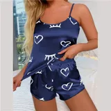 Conjunto de pijama de dos piezas compuesto por una musculosa de tirantes finos y un short, confeccionado en satén con acabado brillante. Presenta un estampado de corazones y figuras abstractas en color blanco sobre una base azul marino.