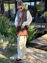 Chaleco tejido de punto en color chocolate, con cuello redondo y diseño sin mangas. Presenta un aplique frontal decorativo compuesto por tres figuras en forma de rombo en tonos tierra, bordeadas con hilo crudo.