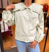 Camisa verde menta con amplio cuello marinero con volados, mangas largas y abotonadura frontal con botones nacarados.