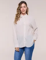 Camisa Magaschoni de silueta holgada y tejido texturizado color blanco, con cuello camisero, cierre frontal de botones, mangas largas con presilla para arremangar y diseño asimétrico con espalda más larga.