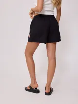 Short negro de algodón y lino con cintura elástica ajustable con cordón y parche bordado en la pierna derecha.