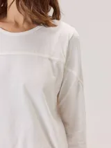 Remera de algodón con cuello redondo y manga larga. Presenta un diseño con costuras horizontales a la altura del pecho y costuras verticales en las mangas, brindando un detalle distintivo a la prenda.