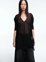 Sweater tipo túnica de tejido liviano con sutil transparencia y destellos brillantes. Presenta escote en V, mangas largas relajadas y un corte amplio con largo generoso.