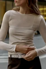 Camiseta de manga larga color beige, con cuello redondo y detalle de camiseta interior en el mismo tejido. Tiene un bajo asimétrico y corte slim fit.