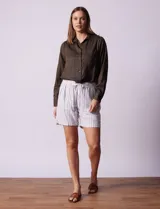 Short blanco con rayas verticales grises, de lino y rayón. Tiene pretina ancha elastizada con lazo de ajuste y bolsillos delanteros.