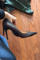 Zapato de tacón alto con punta fina y estampado de piel de serpiente en tonos marrones.