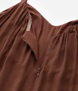 Mono largo de viscosa color marrón, con escote redondo fruncido, tirantes finos y cintura ajustable con lazo del mismo tejido. Presenta un corte holgado y fluido en las piernas.