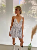 Mono corto de tela floreada azul y blanco, con escote en V, breteles finos y lazo en la cintura.