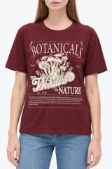 Remera negra de algodón, manga corta, con cuello redondo y diseño gráfico estampado en el pecho que incluye un sol, flores y la leyenda 'Since 1973'.