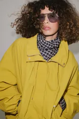 Cazadora bomber de cuello subido ajustable con cordones, manga larga con puños elásticos y cierre frontal con cremallera y botones a presión ocultos bajo solapa. Cuenta con bolsillos delanteros y diseño holgado.