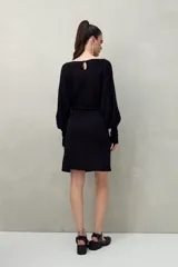 Vestido corto color dorado de punto con brillo integrado en la trama. Diseño de mangas amplias, falda ajustada y lazo frontal que acentúa la cintura.