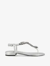 Sandalia plateada con tira en el dedo y diseño entrelazado con apliques de strass. Cuenta con pulsera ajustable en el talón y una base plana de leve altura.