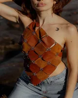 Top halter dorado con diseño asimétrico confeccionado en piezas unidas por ojales metálicos.