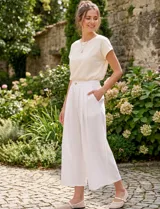 Pantalón palazzo de lino y viscosa, color blanco, de tiro alto y silueta amplia. Presenta pinzas frontales, bolsillos laterales y cierre con botón.