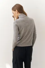 Rompeviento color beige con rayas horizontales finas en marrón, cuello alto y mangas largas.