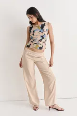 Pantalón ancho de tiro alto, color beige, confeccionado en fibrana con estampado abstracto en tonos oscuros y claros.