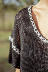 Vestido corto tejido en lurex negro con cuello redondo y mangas cortas.