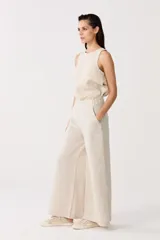 Pantalón de lino color beige, de cintura alta con elástico, bolsillos laterales y corte palazzo.